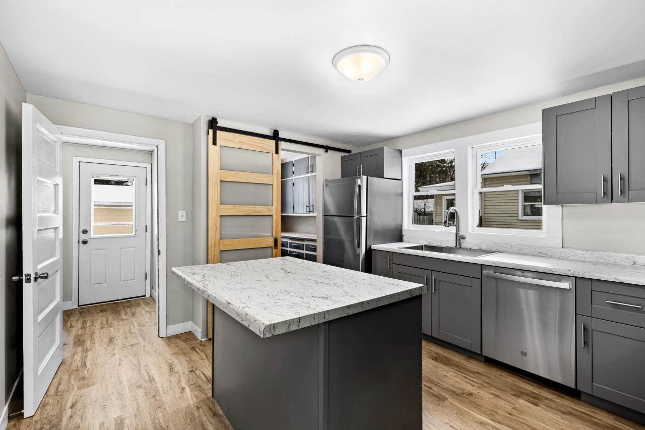 310 3rd Street Cloquet, MN 55720 - Photo 14 of 39 Kitchen with a barn door, gray cabinets, stainless steel appliances, a center island, and light wood-style floors