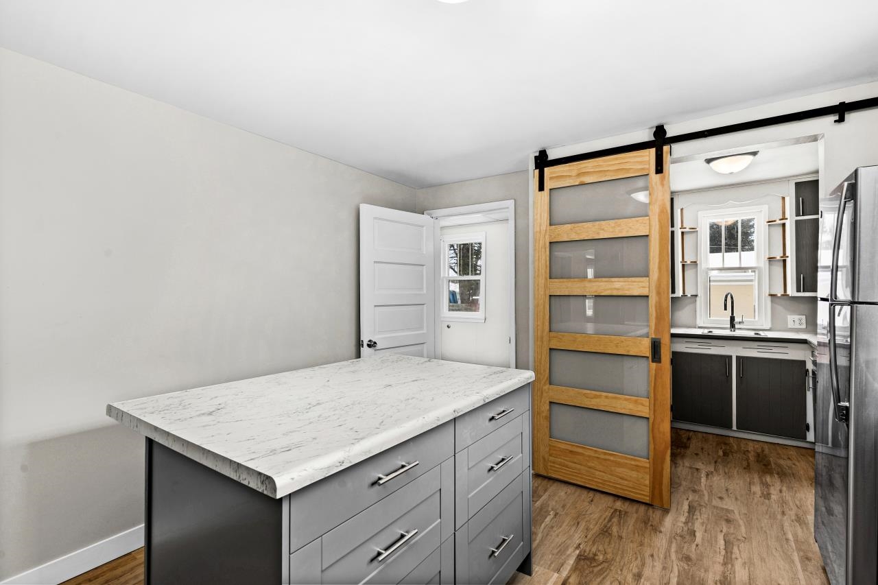 310 3rd Street Cloquet, MN 55720 - Photo 16 of 39 Kitchen with a barn door, light countertops, light wood-style flooring, a kitchen island, and two tone cabinetry