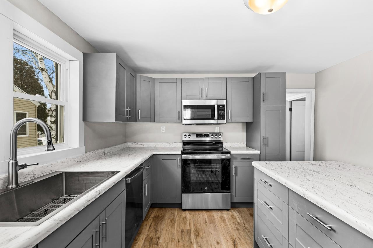 310 3rd Street Cloquet, MN 55720 - Photo 21 of 39 Kitchen with gray cabinets, stainless steel appliances, light wood-type flooring, and light stone countertops