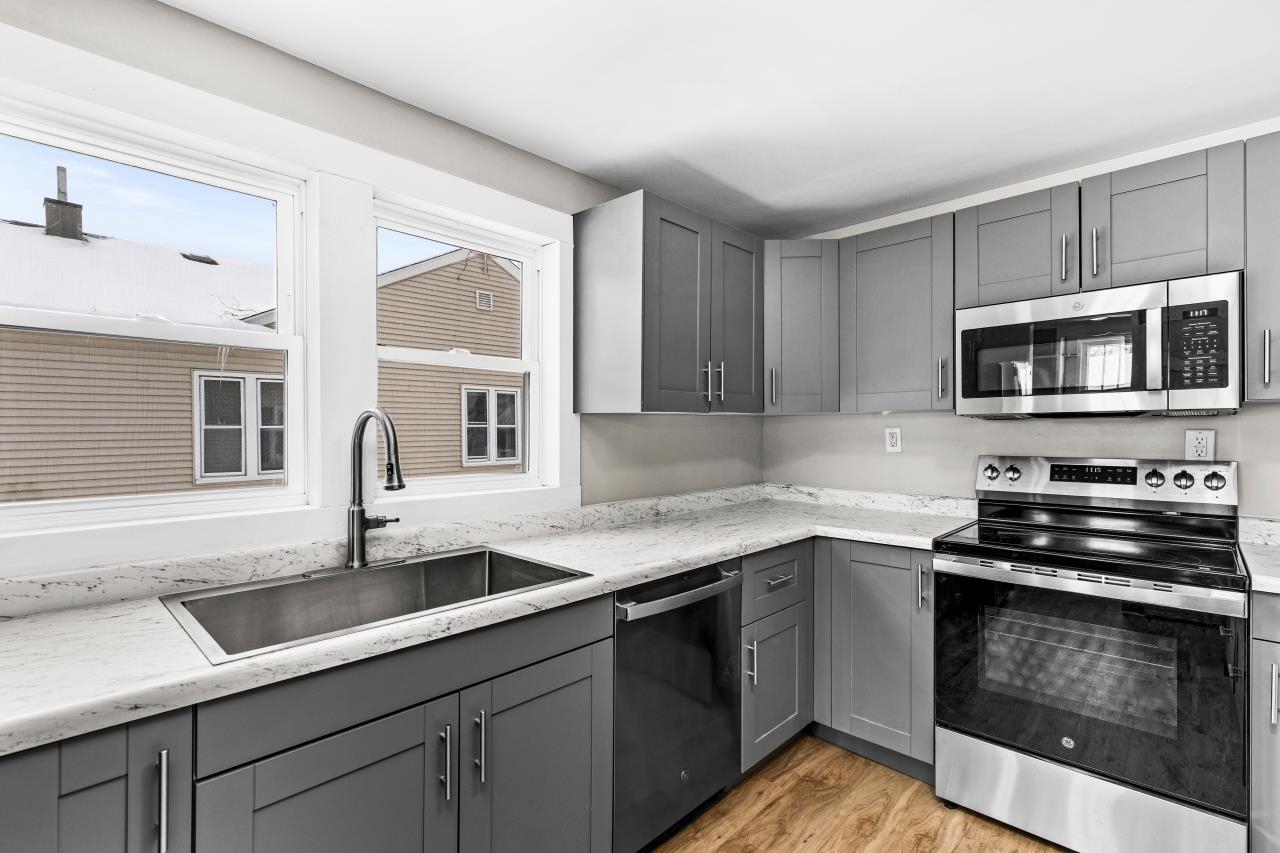 310 3rd Street Cloquet, MN 55720 - Photo 23 of 39 Kitchen with gray cabinetry, stainless steel appliances, light stone countertops, and light wood finished floors