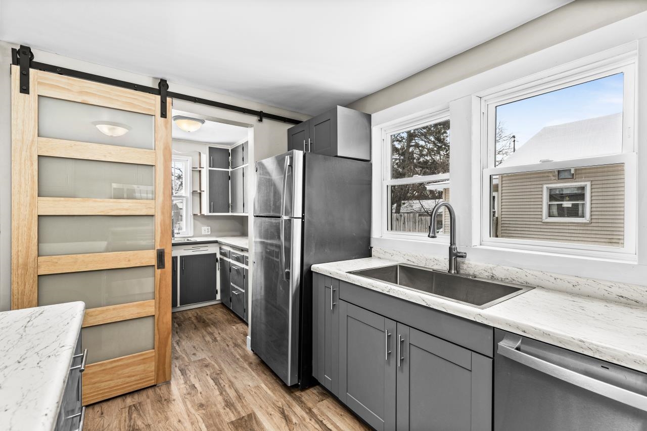 310 3rd Street Cloquet, MN 55720 - Photo 24 of 39 Kitchen with gray cabinetry, a barn door, stainless steel appliances, and light stone counters