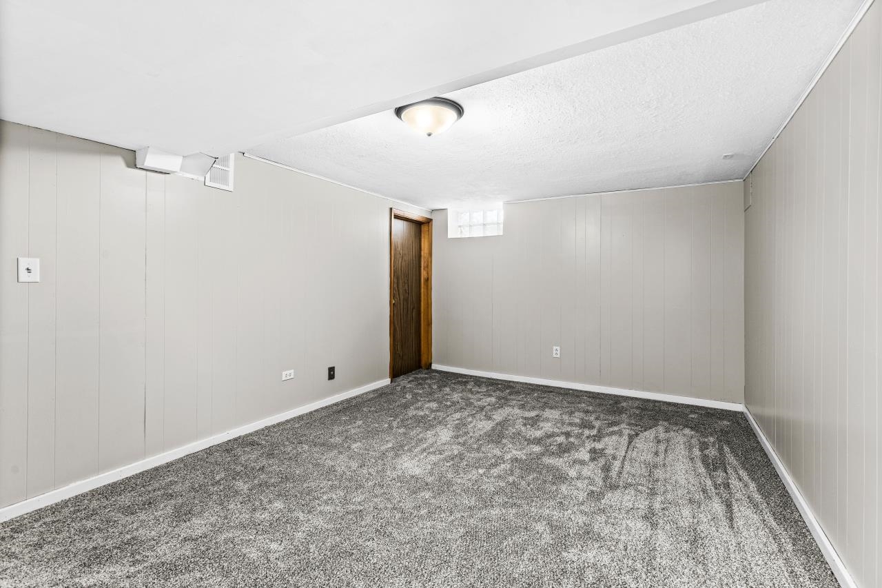 310 3rd Street Cloquet, MN 55720 - Photo 25 of 39 Below grade area with wooden walls, dark colored carpet, and a textured ceiling