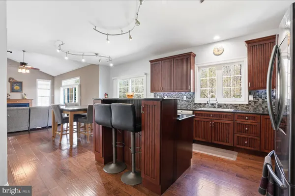 a kitchen with stainless steel appliances granite countertop a refrigerator a stove top oven and a dining table with wooden floor