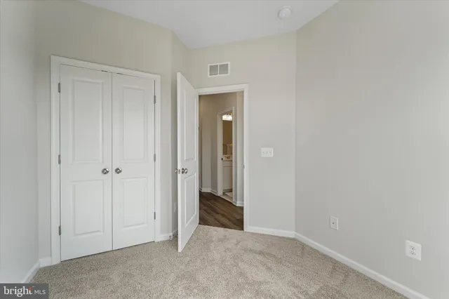 a view of an empty room with closet and mirror