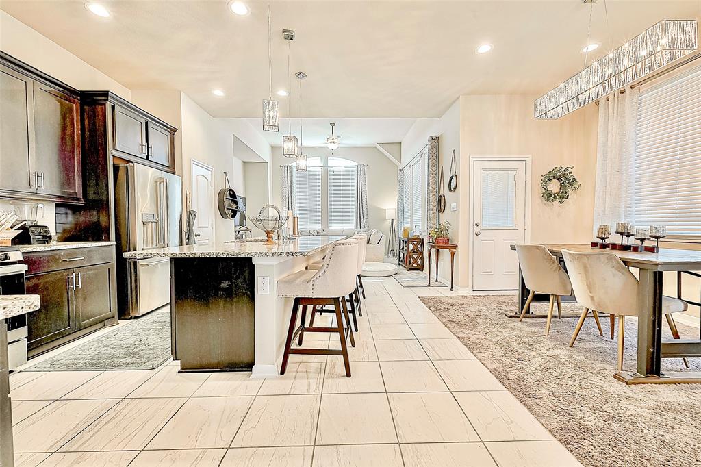 a living room with stainless steel appliances kitchen island granite countertop a table chairs and a refrigerator