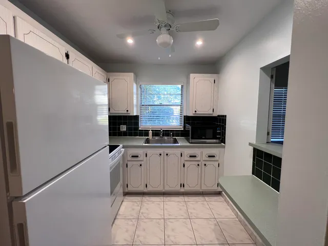 a large kitchen with granite countertop a stove a sink and a microwave