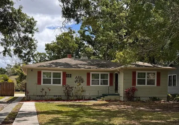 a front view of a house with a garden and tree