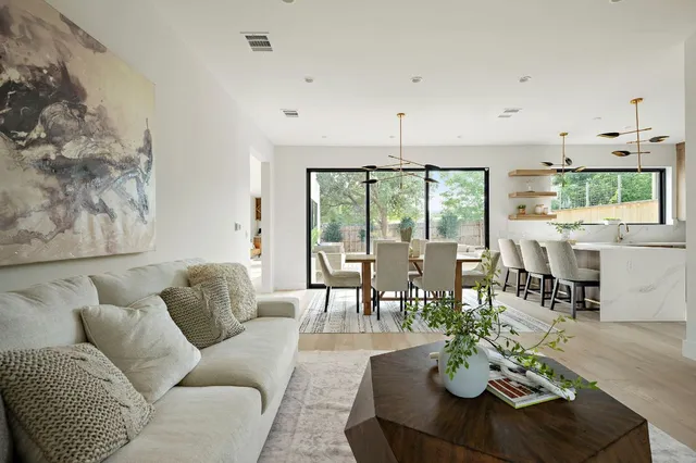 a living room with furniture kitchen view and a large window