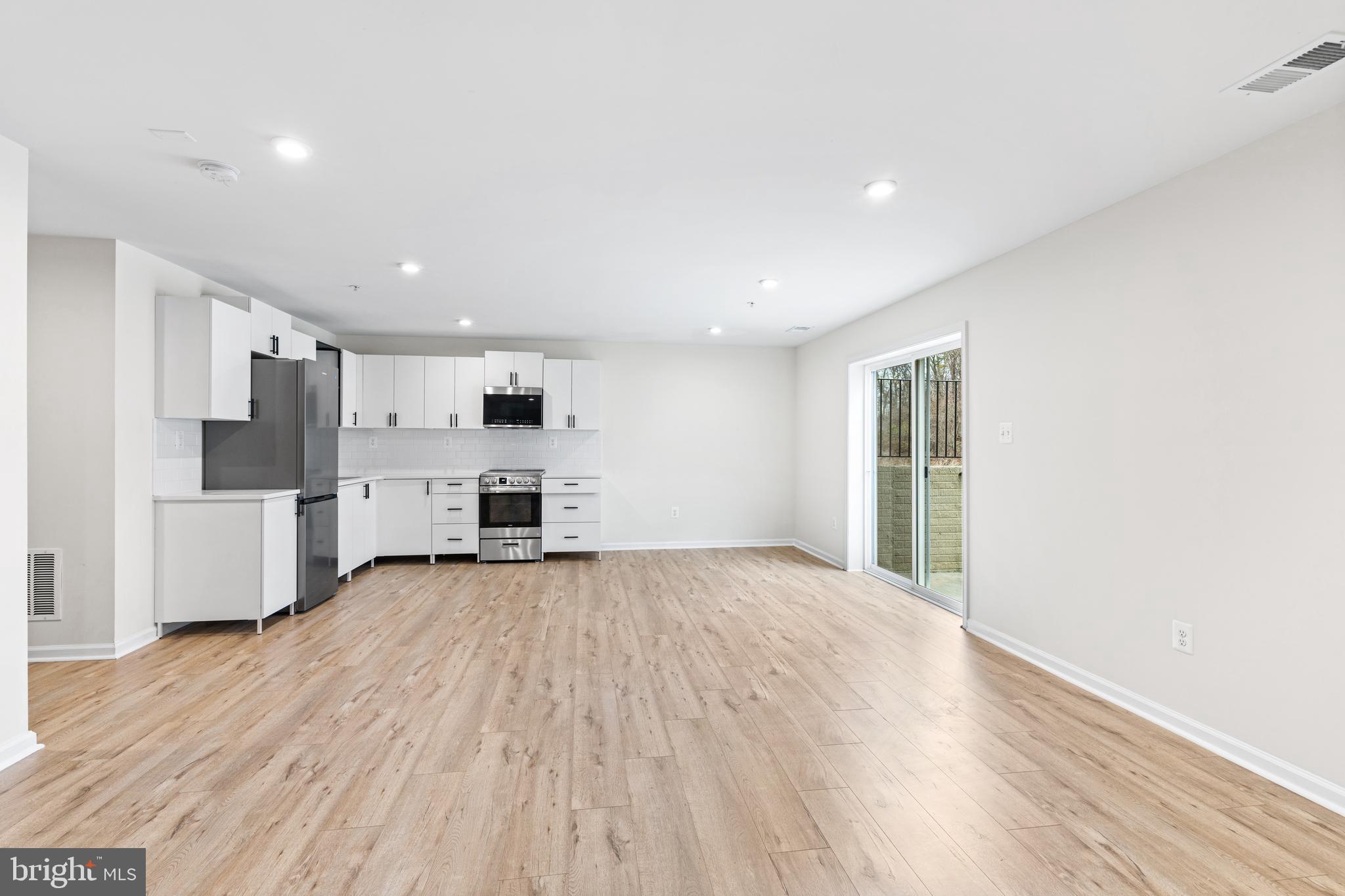 a view of a kitchen with a fridge and wooden floor