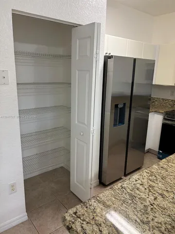 a view of a refrigerator in kitchen and an empty room