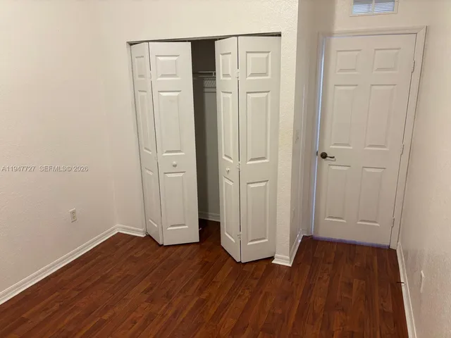 an empty room with wooden floor and closet area