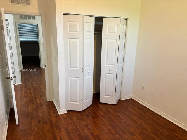 an empty room with wooden floor and closet