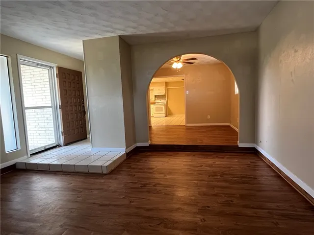 a view of an empty room with glass door and wooden floor