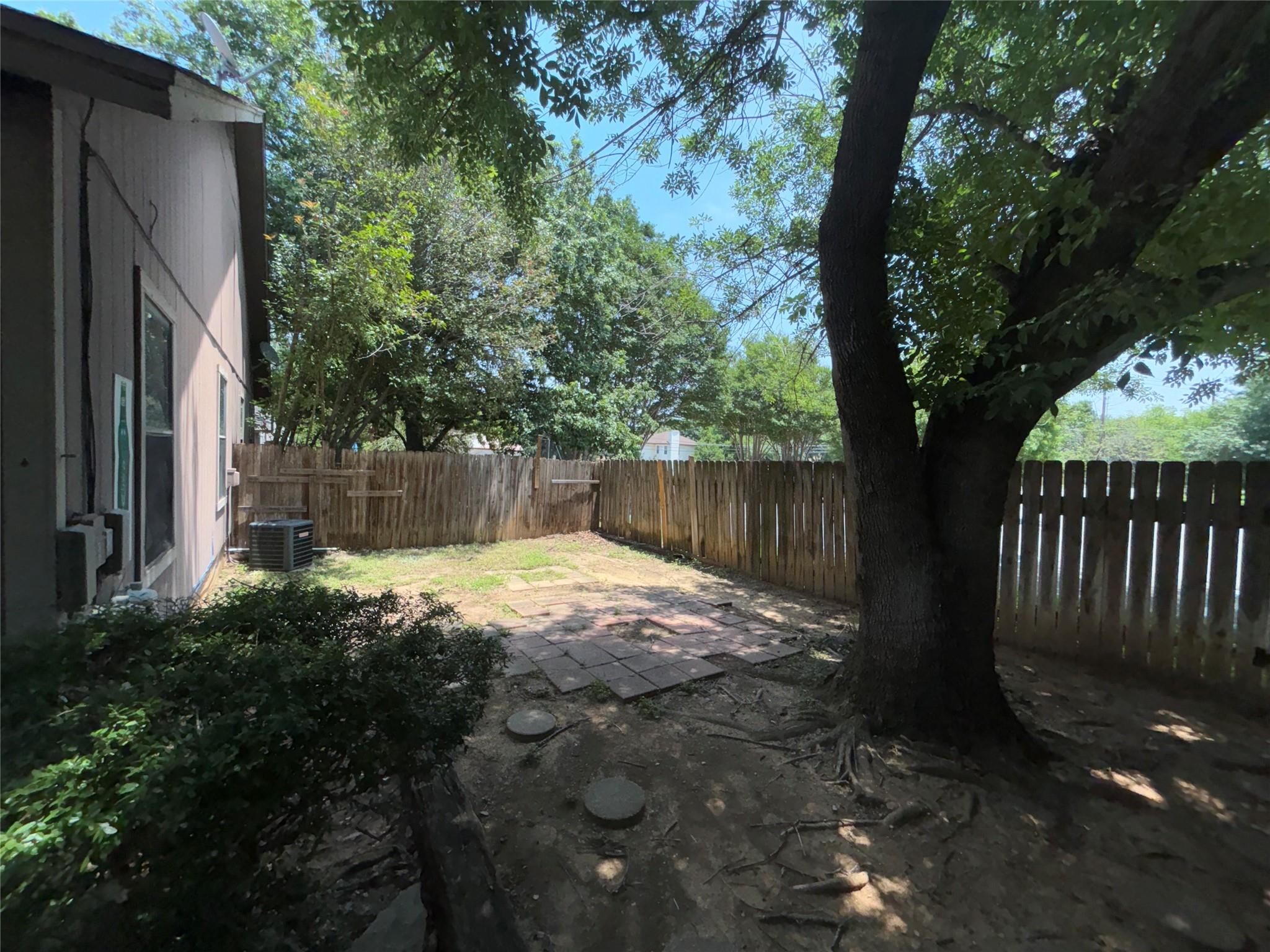 2033 Redwing Way Round Rock, TX 78664 - Photo 13 of 13 Private backyard space featuring a wood fence, mature tree, and partial paver patio