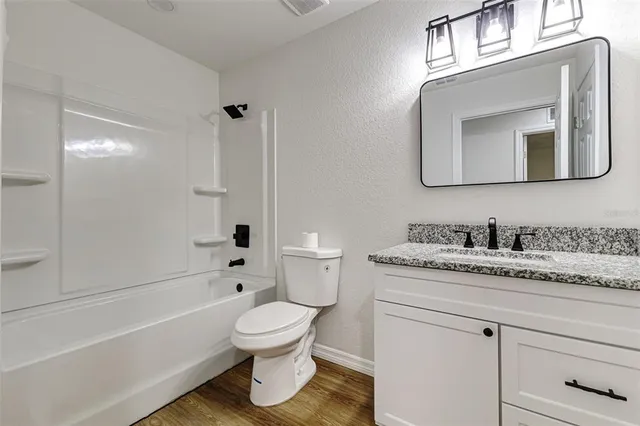 a bathroom with a granite countertop toilet sink and mirror
