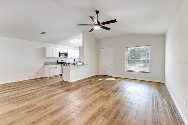 a view of empty room with wooden floor and window