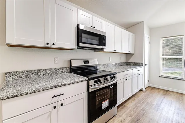 a kitchen with granite countertop wooden cabinets and a stove top oven