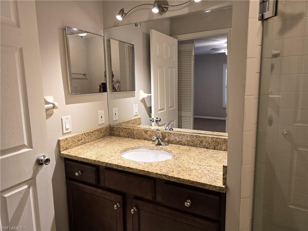 605 Squire Circle, Unit 203 Naples, FL 34104 - Photo 15 of 36 a bathroom with a granite countertop sink and a mirror