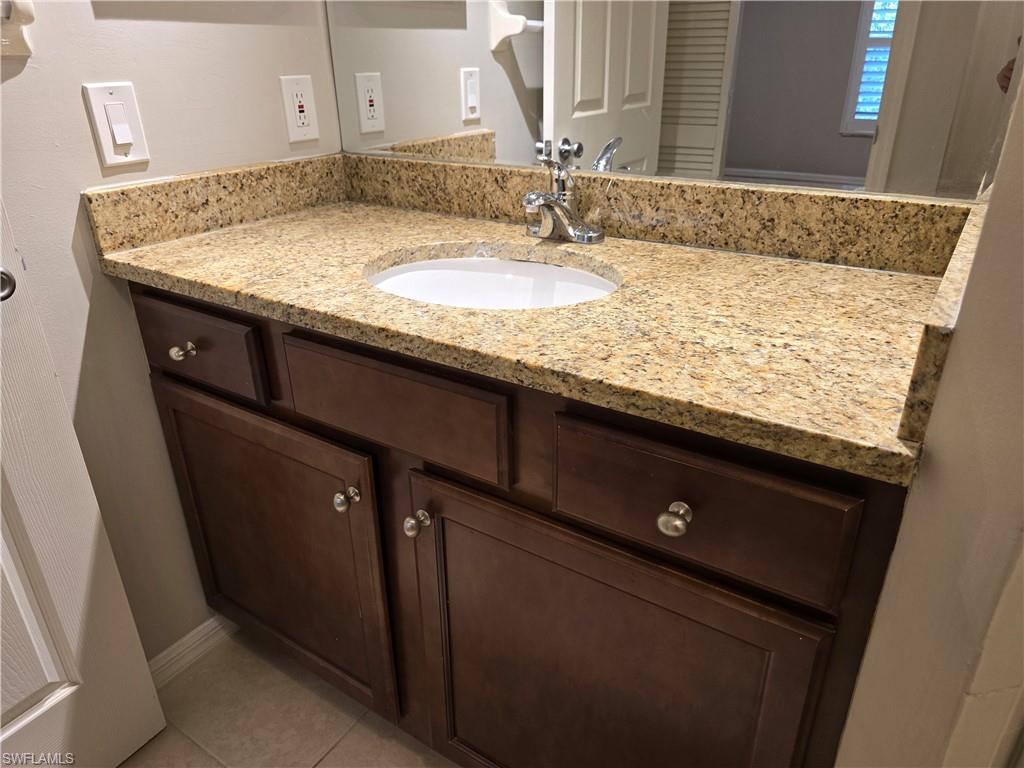 605 Squire Circle, Unit 203 Naples, FL 34104 - Photo 16 of 36 a bathroom with a granite countertop sink and mirror