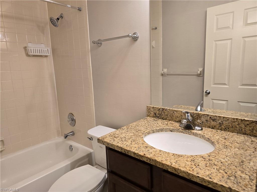 605 Squire Circle, Unit 203 Naples, FL 34104 - Photo 20 of 36 a bathroom with a granite countertop sink toilet and shower