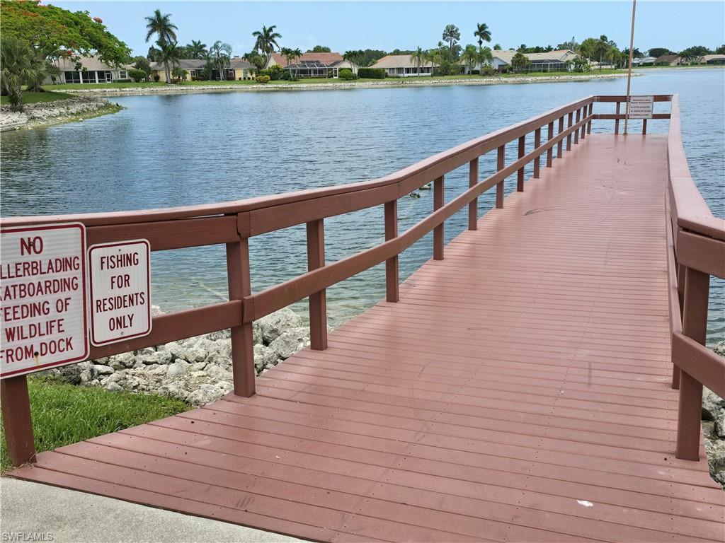 605 Squire Circle, Unit 203 Naples, FL 34104 - Photo 34 of 36 a view of wooden deck and lake with outdoor seating