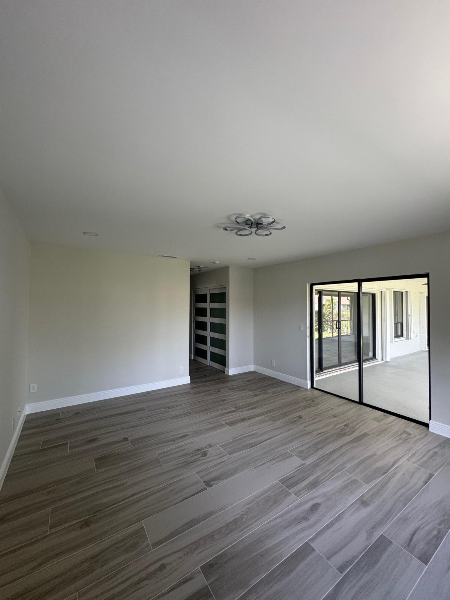 8711 Eagle Run Drive Boca Raton, FL 33434 - Photo 7 of 17 an empty room with wooden floor and windows