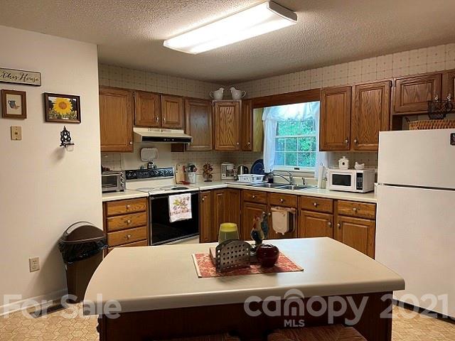 224 Lynch Street Rutherfordton, NC 28139 - Photo 2 of 23 a kitchen with granite countertop a refrigerator a stove a sink dishwasher a dining table and chairs with wooden floor