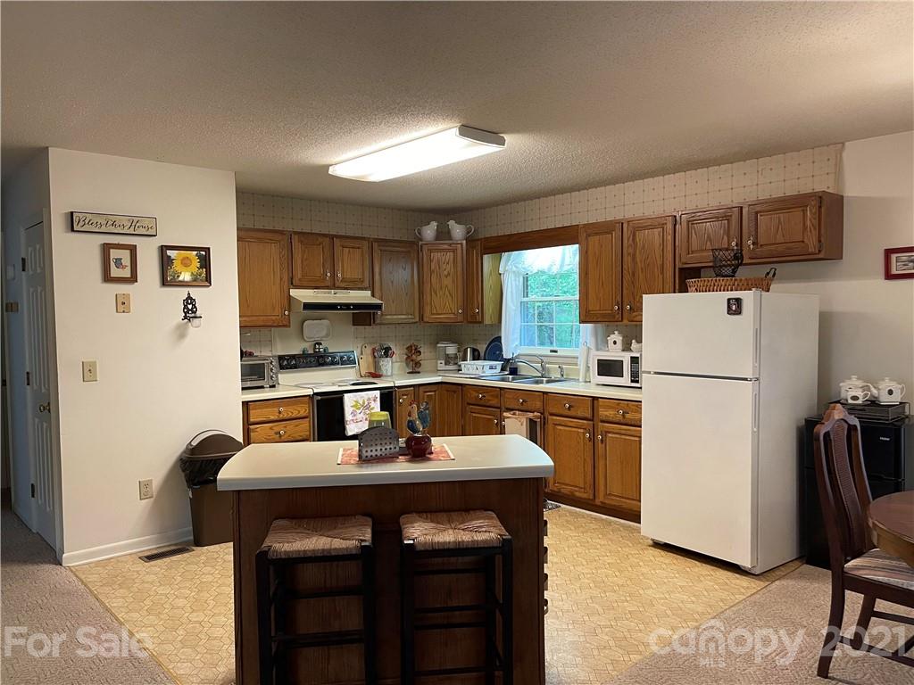 224 Lynch Street Rutherfordton, NC 28139 - Photo 3 of 23 a kitchen with refrigerator a stove a sink and cabinets