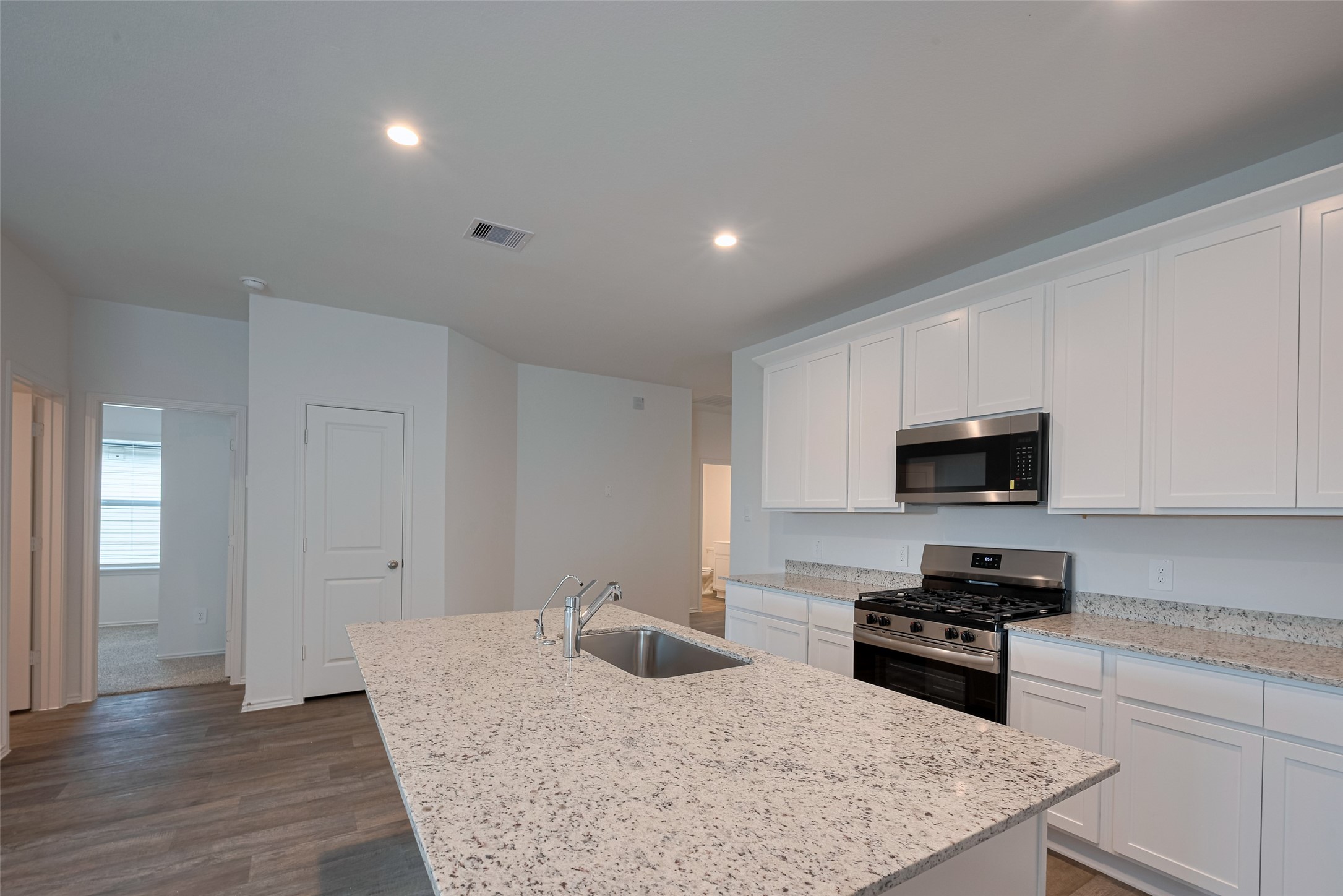 30910 Rockstock Road Fulshear, TX 77441 - Photo 12 of 33 Sleek white cabinetry above and below provides ample storage, while generous countertops offer space to prep, serve, and enjoy. The clean design enhances the kitchen’s streamlined appeal.