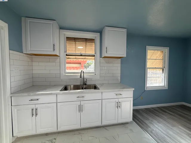 a kitchen with white cabinets and sink