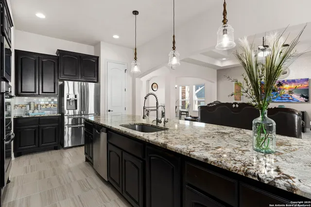 a kitchen with stainless steel appliances kitchen island granite countertop a sink refrigerator and cabinets