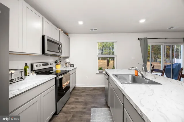 a kitchen that has a lot of cabinets in it with granite countertop a sink and dishwasher a stove top oven with wooden floor