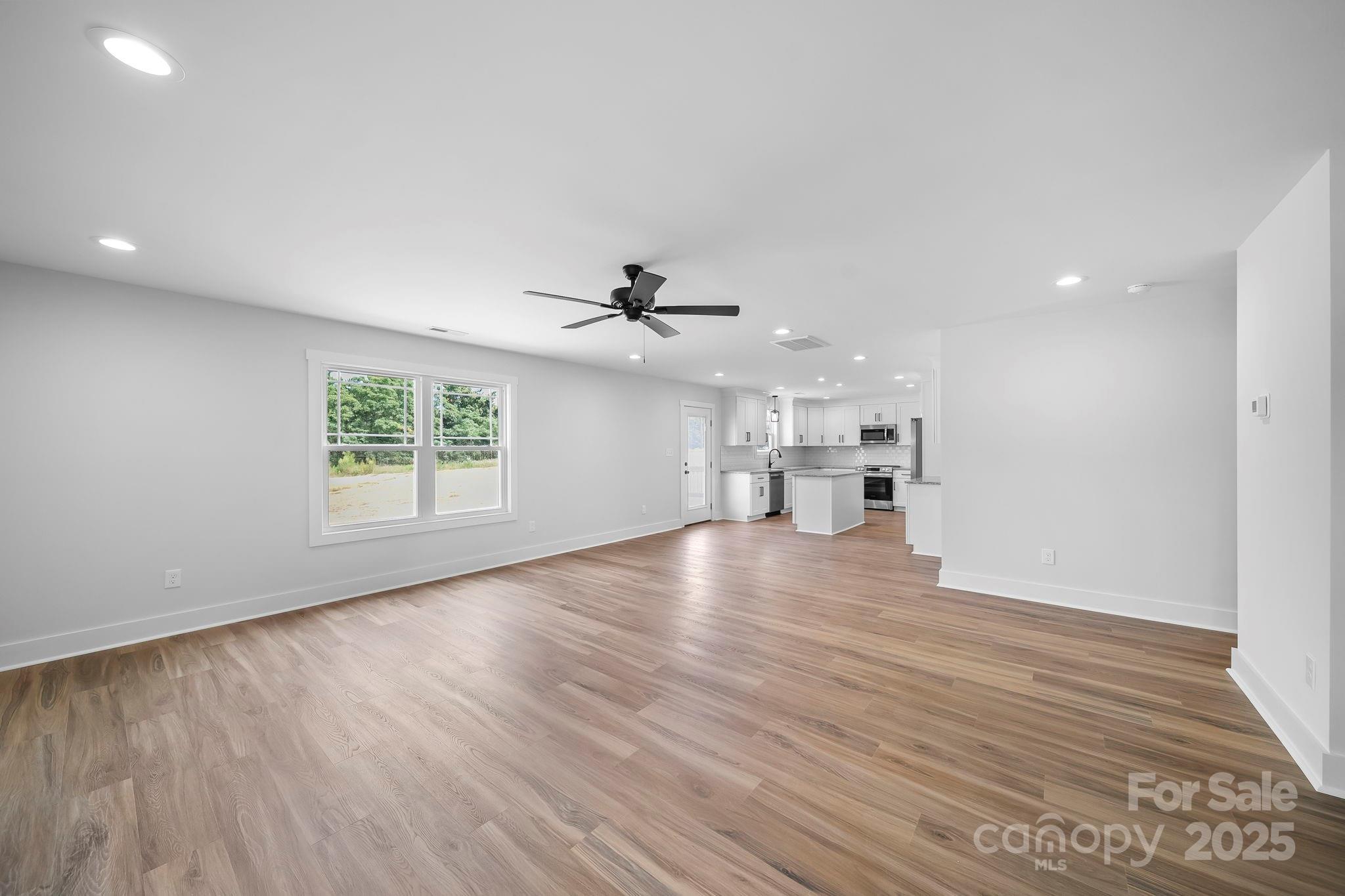 1312 Austin Chaney Road Wingate, NC 28174 - Photo 11 of 47 an empty room with wooden floor a ceiling fan wooden floor and windows
