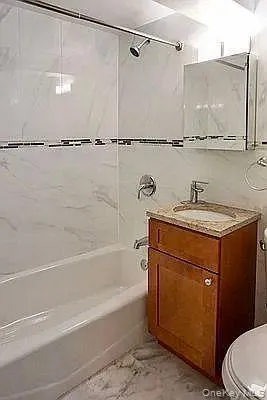 a bathroom with a granite countertop sink a toilet and shower