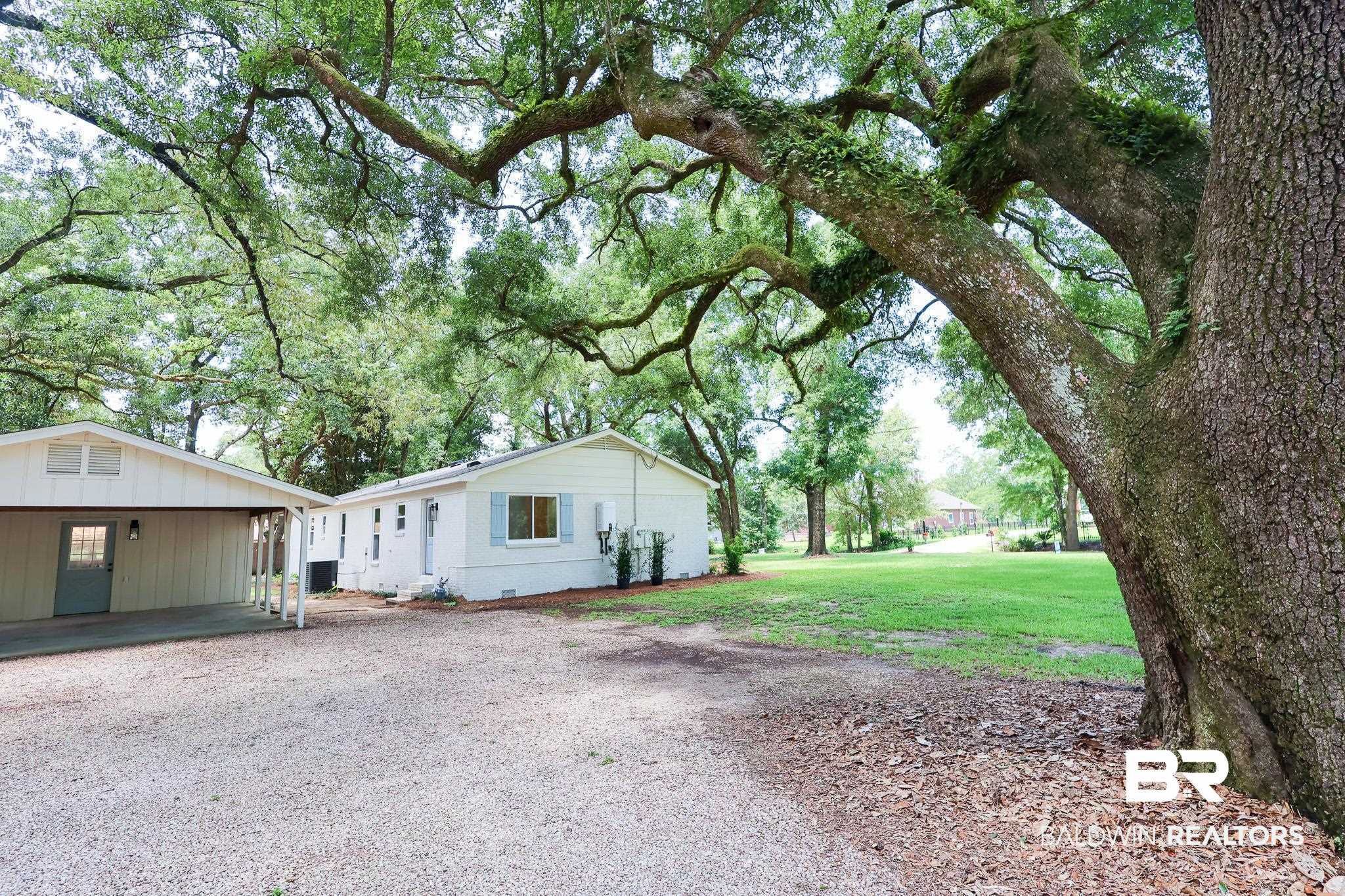 12190 Pecan Grove Street Magnolia Springs, AL 36555 - Photo 32 of 45 View of side of property featuring a lawn and a carport