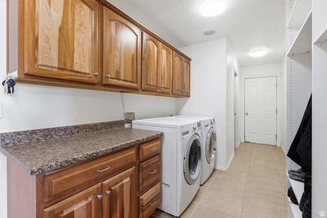 860 West 2980th Street South Logan, UT 84321 - Photo 14 of 38 Laundry area featuring wood-finish cabinetry, a speckled countertop, and tiled flooring
