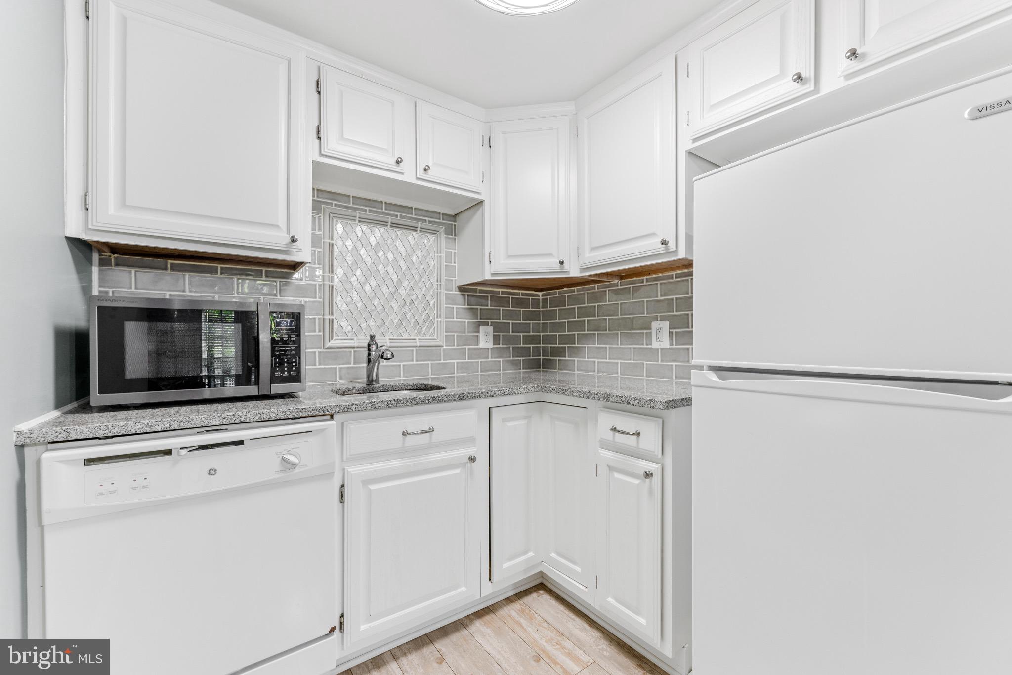 7140 Stone Throw Way Elkridge, MD 21075 - Photo 2 of 9 a kitchen with white cabinets and stainless steel appliances