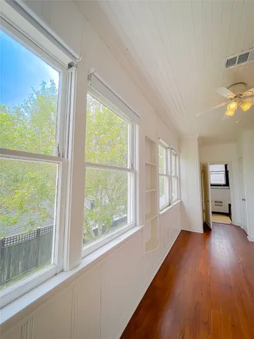 a view of empty room with wooden floor and fan