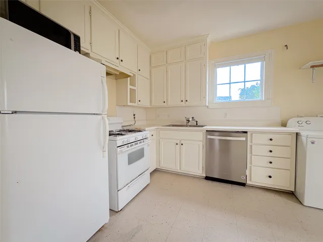 a kitchen with white cabinets and white appliances