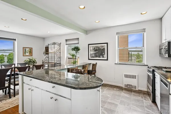 a kitchen with stainless steel appliances granite countertop a stove a sink a microwave a dining table and chairs