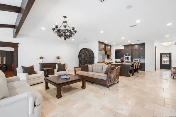 a living room with stainless steel appliances kitchen island granite countertop a table chairs in it and wooden floors