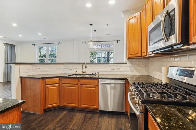 a kitchen with stainless steel appliances granite countertop wooden cabinets stove and sink