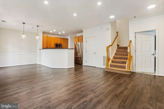 a view of an empty room with wooden floor and stairs