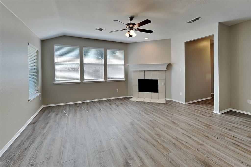 7016 Raintree Way Denton, TX 76210 - Photo 2 of 18 an empty room with wooden floor a ceiling fan and windows