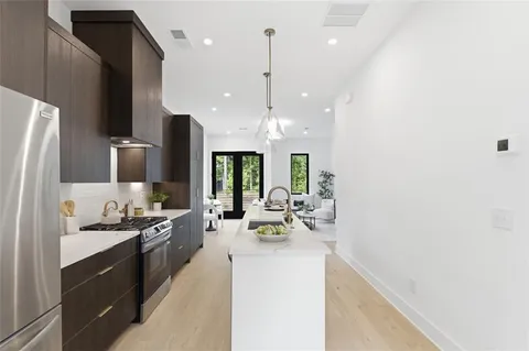 a view of a kitchen with kitchen island a sink stainless steel appliances and windows