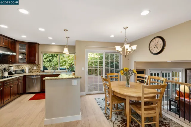 a kitchen with kitchen island granite countertop a stove a oven a dining table and chairs with wooden floor