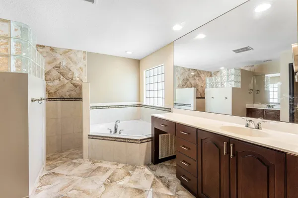 a spacious bathroom with a tub sink and mirror