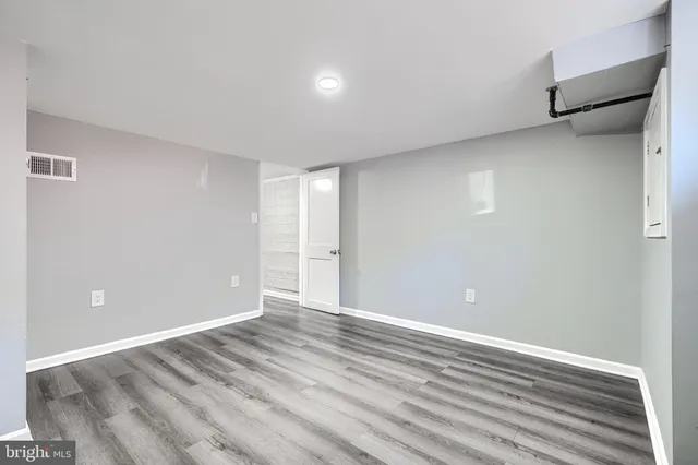 a view of an empty room with wooden floor and stairs