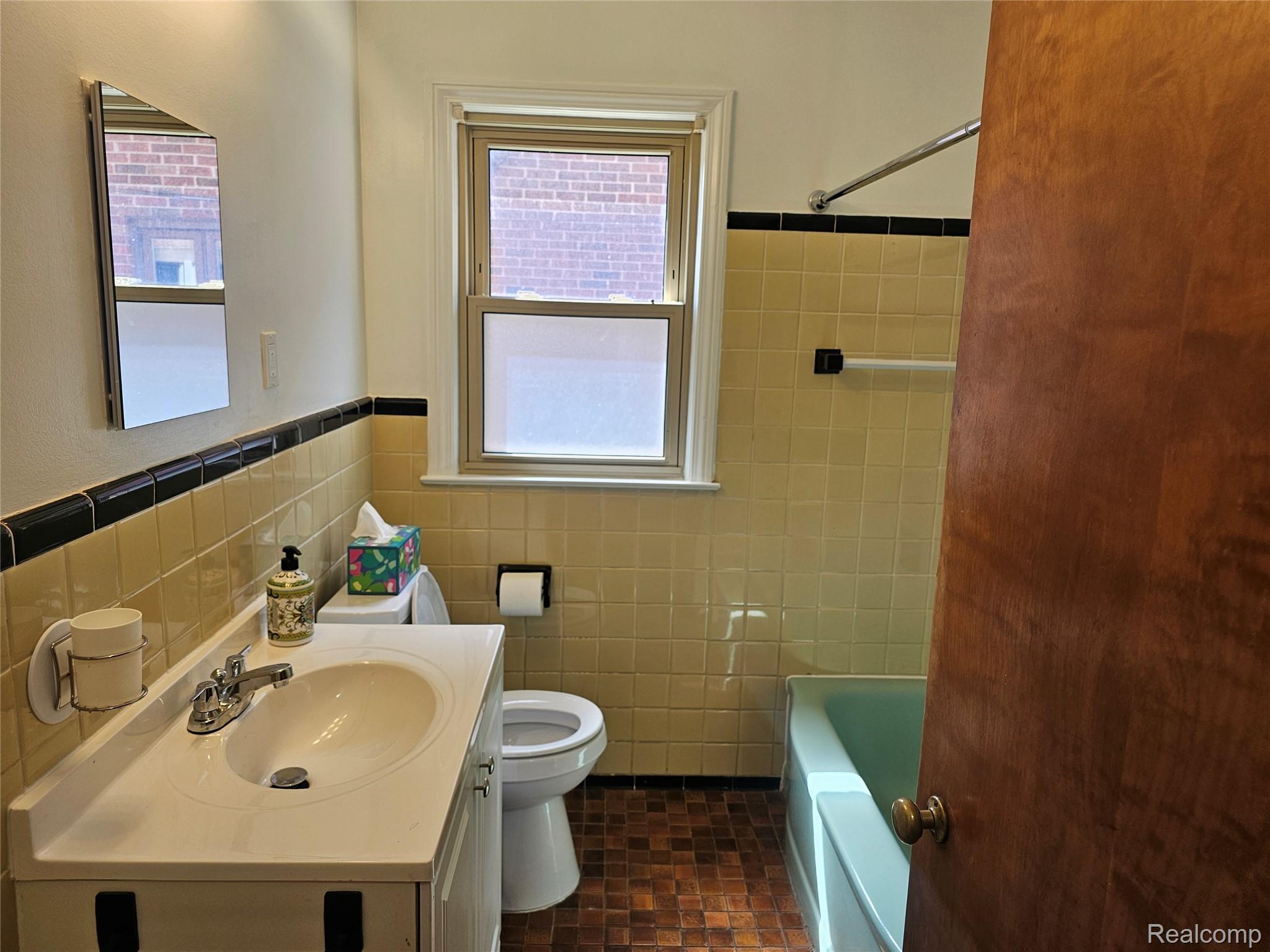5240 Harvard Road Detroit, MI 48224 - Photo 12 of 18 Bathroom featuring a single window, a light-colored vanity with an integrated sink, a commode, and a bathtub with tiled surround