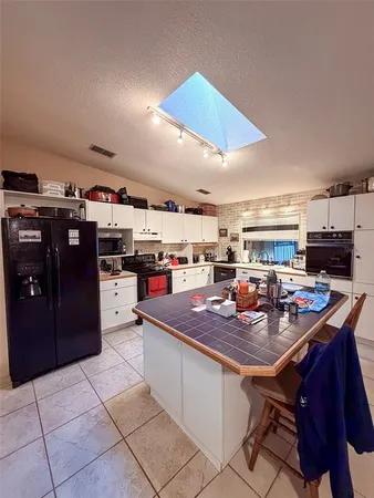 a kitchen with stainless steel appliances granite countertop a table chairs and a refrigerator